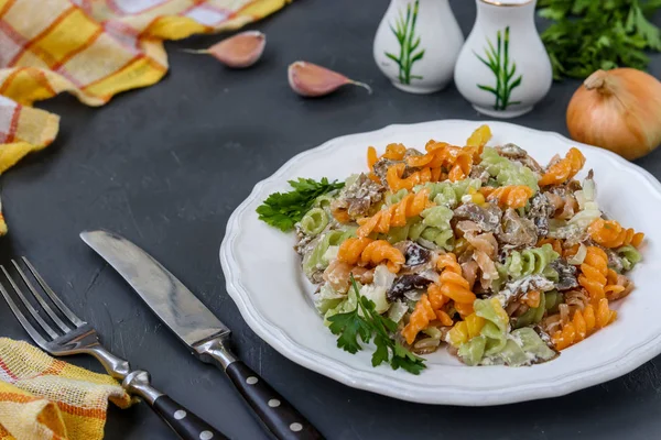 Fusilli разноцветная паста с овощами в белой тарелке на темном фоне, горизонтальная ориентация, избирательный фокус — стоковое фото