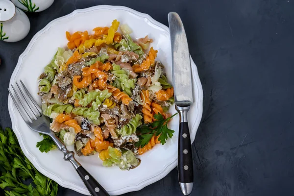 Fusilli разноцветная паста с овощами в белой тарелке на темном фоне, горизонтальная ориентация, вид сверху — стоковое фото