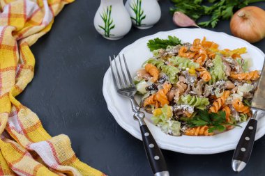 Koyu arka plan üzerinde beyaz bir tabak ta sebze ile Fusilli çok renkli makarna, seçici odak