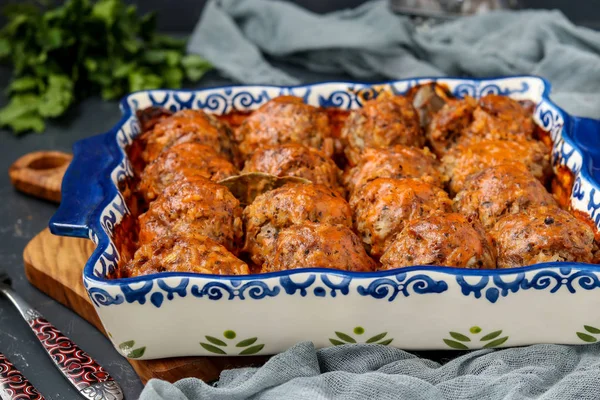 Albóndigas en crema agria y salsa de tomates en forma de cerámica sobre un fondo oscuro, orientación horizontal — Foto de Stock