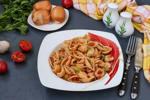 Conchiglie cáscaras de pasta italiana con tomates cherry y salsa de tomate sobre fondo oscuro, orientación horizontal, primer plano — Foto de Stock