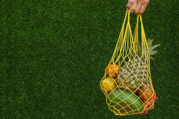 Тропические фрукты: манго, папайя, ананас, дракон и маракуйя фрукты в Yellow Shopping Textile мешок на зеленом фоне, горизонтальная ориентация, копировальное пространство — стоковое фото