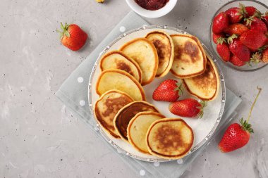 Ev yapımı kahvaltı: Çilek reçelli krep ve beton arka planda gri peçete, üst manzara, metin için alan