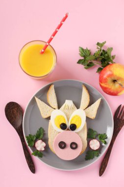 Komik boğa şeklinde sosis ve yumurtalı sandviç, pembe arka planda yeni 2021 'in sembolü, çocuklar için aşçılık fikri kahvaltısı, dikey format.