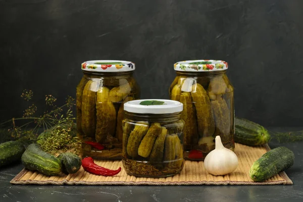 Gemarineerde komkommers in potten bevinden zich op een tafel, op een donkere achtergrond. Oogst voor de winter. Sluitingsdatum — Stockfoto