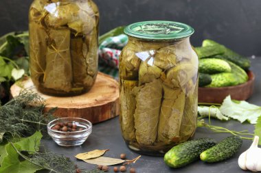 Koyu bir arka planda cam kavanozlarda salatalık konservesi ve kış için hasat.