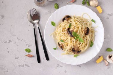 Mantarlı spagetti ve gri arka planda beyaz tabakta fesleğen, Üst Manzara, metin için boşluk