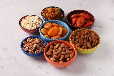 Kurutulmuş kayısı, kuru üzüm, yer fıstığı, badem, gri beton arka planda ceviz.