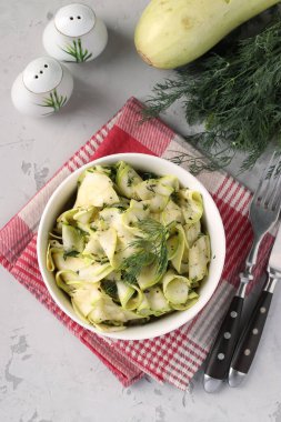 Genç kabak atıştırmalıkları dereotu ve sarımsak ile ince kurdeleler halinde kesilmiş, gri arka plan, Üst Manzara, Dikey Biçim