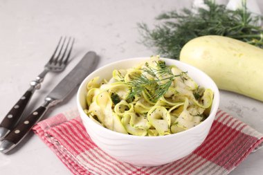 Dereotu, sarımsak ve gri arka planda ince kurdeleler halinde kesilmiş genç kabak atıştırmalıkları.