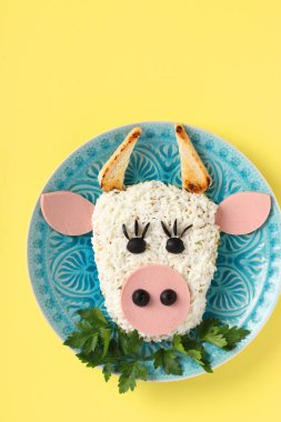 Sarı zemin üzerinde 2021 için şenlikli boğa şekilli salata, yeni yıl için sembolik yiyecek, yukarıdan görüş, dikey format