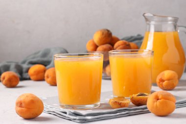 İki bardak hamurlu kayısı suyu ve gri arka planda bir sürahi, yatay format