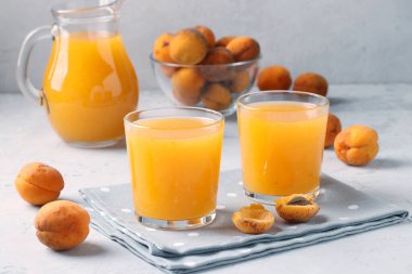 İki bardak hamurlu kayısı suyu ve gri arka planda bir sürahi, yatay format