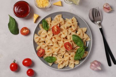 Kiraz domatesli Farfalle makarnası, beyaz arka planda domates sosu ve fesleğen, yakın plan, Üst Manzara