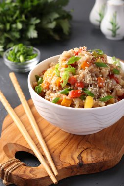 Sebzeli kızarmış pirinç, sarımsak, zencefil ve koyu arkaplanda yeşil soğan. Asya mutfağı. Vejetaryen yemeği, dikey format