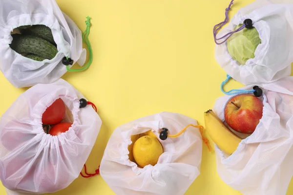 Frutas y verduras en bolsas de malla ecológicas reutilizables sobre fondo amarillo brillante. Espacio para texto, Concepto de cero residuos, Detener la contaminación. — Foto de Stock
