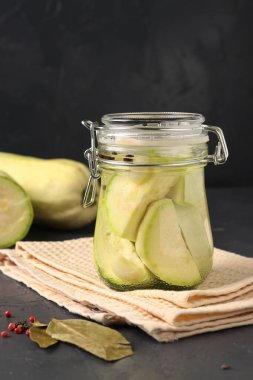 Kavanozda mayalanmış kabak ve koyu arka planda çiğ kabak, vegan diyeti. Dikey biçim.