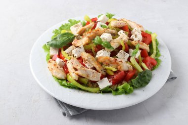 Bulgur salatası, fırında tavuk, dolmalık biber, fesleğen ve beyaz tabakta feta, yakın plan. Yatay biçim