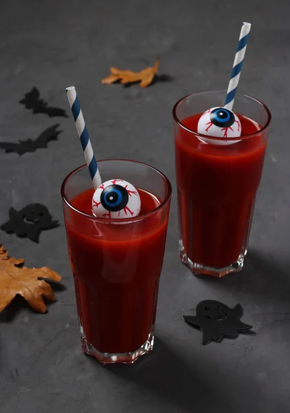 Eyes in glass with tomato cocktail on dark table for Autumn Holiday Halloween. Closeup. Vertical format.