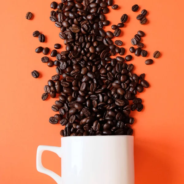 Grãos de café em xícara de café isolado em branco — Fotografia de Stock