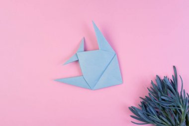 Origami light blue fish on pink minimalistic background clipart