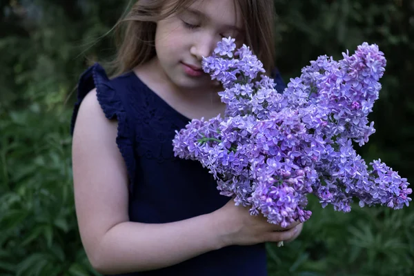Menina bonito cheirando lilás — Fotografia de Stock