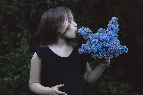 Cute little girl kissing lilac — Stock Photo, Image