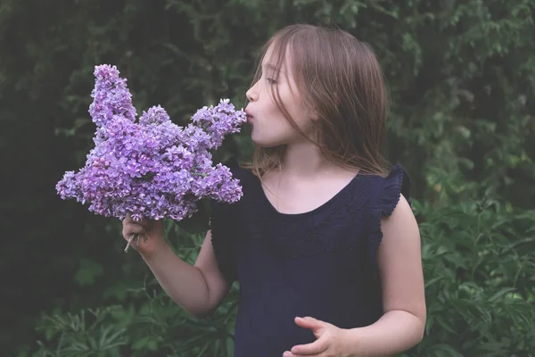 Bonito menina beijando lilás — Fotografia de Stock