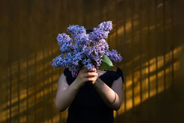 Girl holding lilac bouquet in front of face — Stock Photo, Image