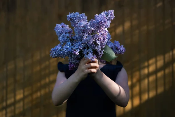Girl holding lilac bouquet in front of face
