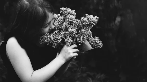 Menina bonito cheirando lilás — Fotografia de Stock