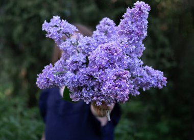 Leylak buketi ile yüz saklayan kız