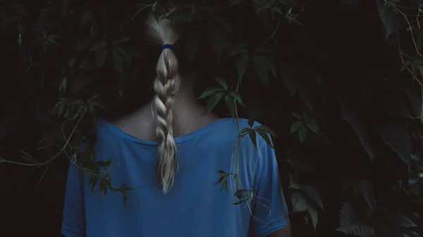 Dívka s blond vlasy na tmavém přírodním pozadí — Stock fotografie