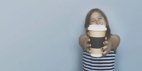 Smiling girl giving, showing coffeecup closeup side view — Stock Photo, Image