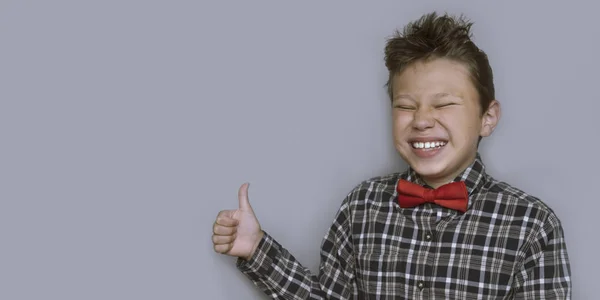 Young boy giving thumbs up portrait on violet background