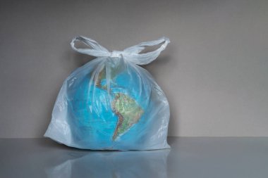 Gri arka plan üzerinde plastik torba içinde Dünya küre