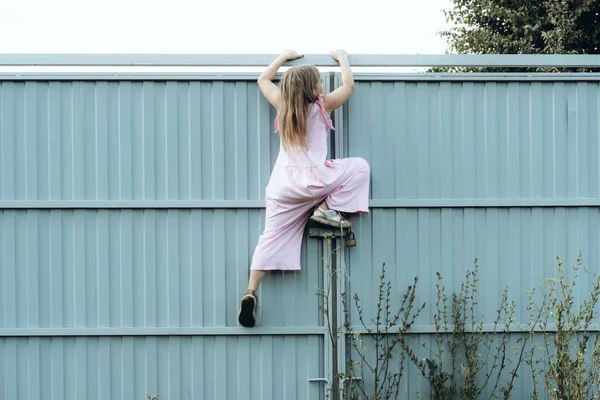 Mädchen klettert Metallzaun im Freien — Stockfoto