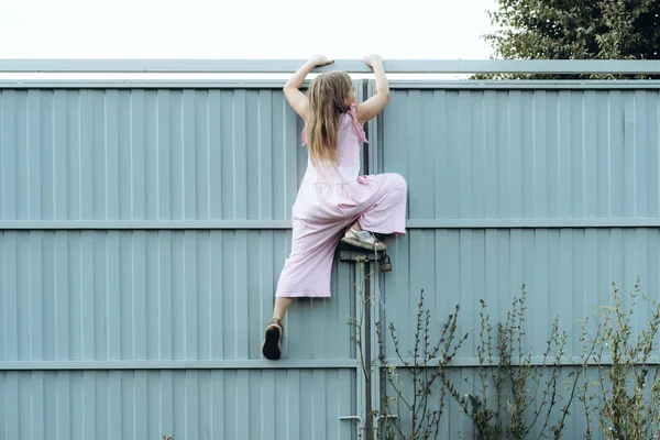 Girl climbing metal fence outdoor