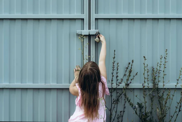 Junges Mädchen öffnet Vorhängeschloss an Metallzaun — Stockfoto