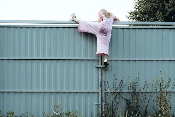 Girl climbing metal fence outdoor — Stock Photo, Image