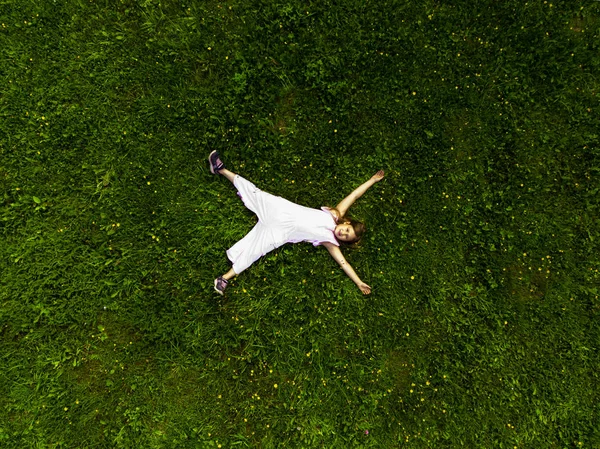 Menina bonito deitado na grama verde no parque — Fotografia de Stock