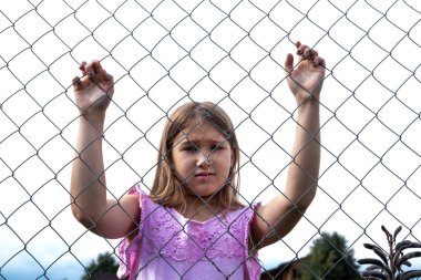 Metal tel örgü çit arkasında Üzgün kız