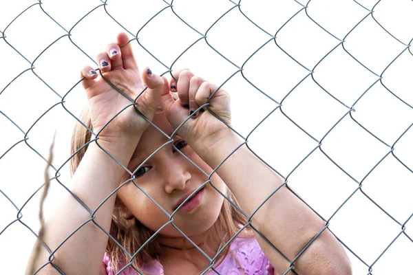 Chica triste detrás de valla de malla de alambre de metal — Foto de Stock
