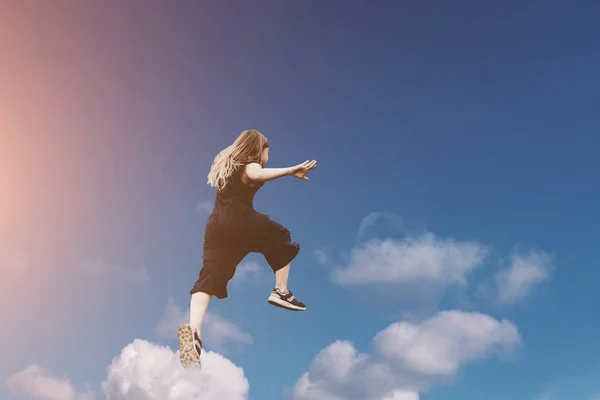 Aranyos lány jumping vicces felhők — Stock Fotó