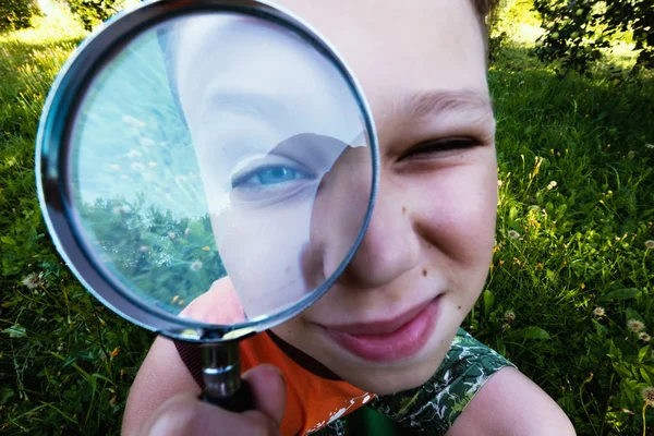 Little boy looking at flower through magnifier — Stock Photo, Image