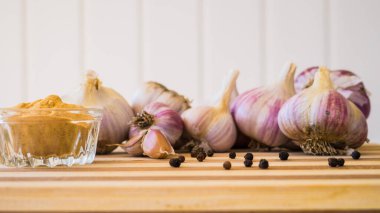 Kahverengi ahşap bir tahtanın üzerinde biber ve sarımsak çeşnili güzel ve büyük bir sarımsak var..