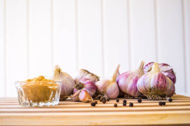 Kahverengi ahşap bir tahtanın üzerinde biber ve sarımsak çeşnili güzel ve büyük bir sarımsak var..