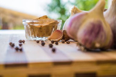 Kahverengi ahşap bir tahtanın üzerinde biber ve sarımsak çeşnili güzel ve büyük bir sarımsak var..