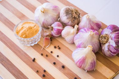 Kahverengi ahşap bir tahtanın üzerinde biber ve sarımsak çeşnili güzel ve büyük bir sarımsak var..