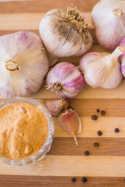 Kahverengi ahşap bir tahtanın üzerinde biber ve sarımsak çeşnili güzel ve büyük bir sarımsak var..